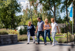 En familie går smilende sammen i solskin på Résidence Lichtenvoorde, en feriepark i Gelderland, Holland.