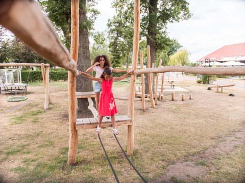 Bambina e adulta giocano insieme su un parco giochi in legno a Résidence Lichtenvoorde, Gelderland, Paesi Bassi.