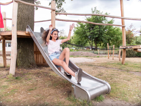 Una niña se desliza felizmente por un tobogán en Résidence Lichtenvoorde, un parque vacacional en Gelderland.