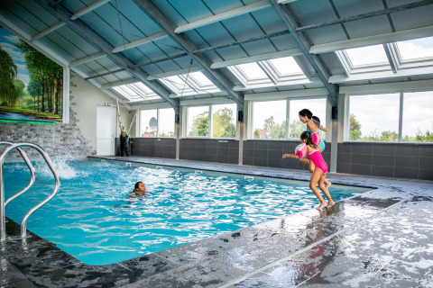 Piscina coperta presso Résidence Lichtenvoorde, bambini felici saltano nell'acqua del parco vacanze.