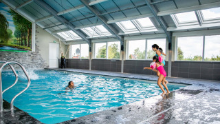 Piscina cubierta en Résidence Lichtenvoorde, niños felices saltando al agua en parque vacacional.