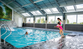 Piscina cubierta en Résidence Lichtenvoorde, niños felices saltando al agua en parque vacacional.