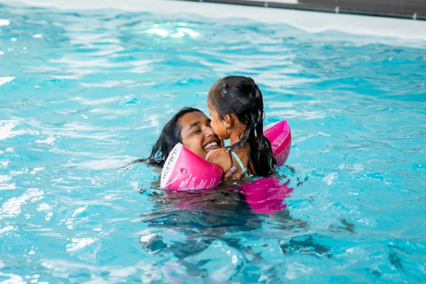 Mamma e figlia sorridono e nuotano insieme nella piscina del Résidence Lichtenvoorde in Gelderland.