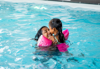 Mamma e figlia sorridono e nuotano insieme nella piscina del Résidence Lichtenvoorde in Gelderland.