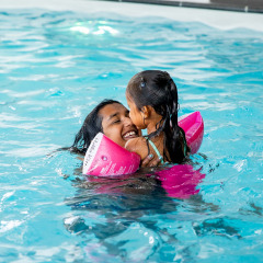 Madre e hija nadan juntas y sonríen en la piscina de Résidence Lichtenvoorde en Gelderland, Países Bajos.