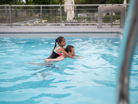 Un uomo nuota in piscina con una bambina sulle spalle a Résidence Lichtenvoorde, Gelderland, Paesi Bassi.