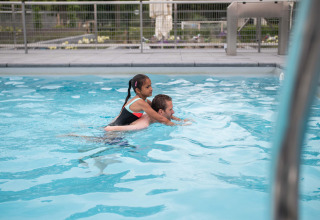 Un uomo nuota in piscina con una bambina sulle spalle a Résidence Lichtenvoorde, Gelderland, Paesi Bassi.