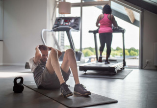 To personer træner indendørs i et fitnesscenter på Résidence Lichtenvoorde feriepark i Gelderland.