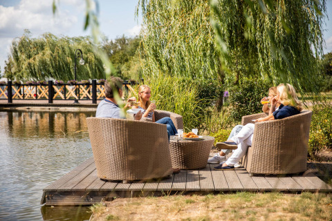Vier mensen drinken en eten bij het water in Résidence Lichtenvoorde, een vakantiepark in Gelderland.