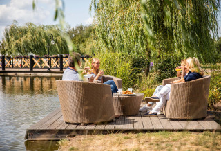 Quattro persone gustano cibo e bevande vicino all’acqua a Résidence Lichtenvoorde, Gelderland.