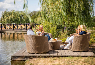 Four people enjoy drinks and snacks by the water at Résidence Lichtenvoorde holiday park, Gelderland.