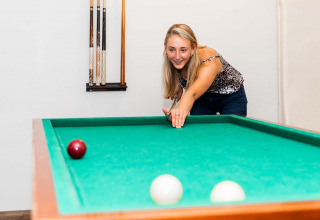 Vrouw speelt biljart aan een groene tafel in Résidence Lichtenvoorde, vakantiepark in Gelderland.
