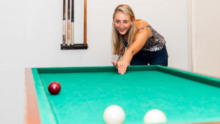 Mujer juega billar en una mesa verde en el parque vacacional Résidence Lichtenvoorde, Gelderland, Países Bajos.