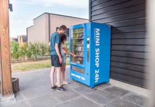 Twee mensen gebruiken een blauwe 24u-automaat buiten bij Résidence Lichtenvoorde in Gelderland, Nederland.