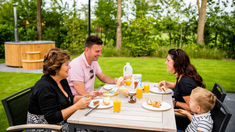 Familie genießt Frühstück im Freien im Résidence de Leuvert Ferienpark in Nord-Brabant, Niederlande.