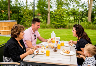Familie genießt Frühstück im Freien im Résidence de Leuvert Ferienpark in Nord-Brabant, Niederlande.
