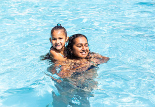 Zwei Kinder spielen und lächeln im Pool im Ferienpark Résidence de Leuvert in Nordbrabant, Niederlande.
