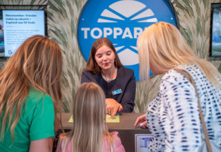 Receptionist hjælper gæster ved indtjekningsskranken på Résidence de Leuvert feriepark i Nordbrabant.
