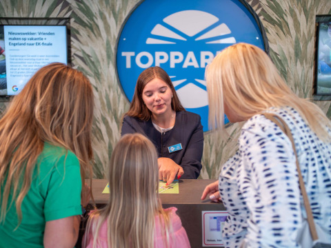 Receptionist hjælper gæster ved indtjekningsskranken på Résidence de Leuvert feriepark i Nordbrabant.