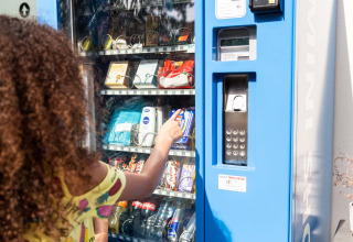 Eine Person wählt einen Snack an einem Automaten im Ferienpark Résidence de Leuvert in Nordbrabant, Niederlande.