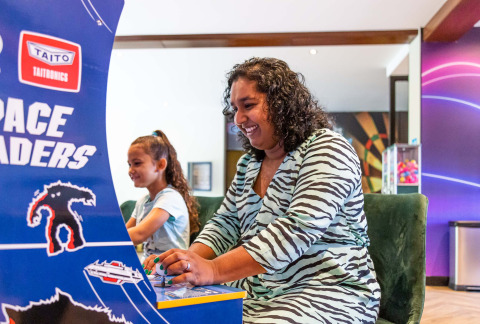 Woman and child enjoy playing a Space Invaders arcade game at Résidence de Leuvert in North Brabant, Netherlands.