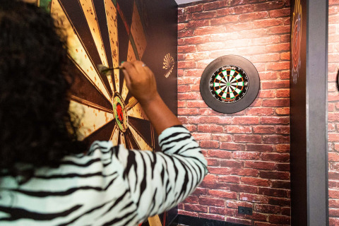 Eine Person spielt Darts in einer Indoor-Umgebung auf dem Ferienpark Résidence de Leuvert, Noord-Brabant.