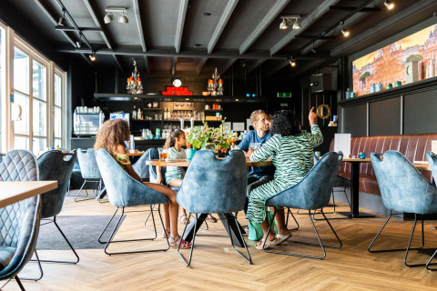Familia disfruta de una comida en un elegante restaurante del parque vacacional Résidence de Leuvert, Países Bajos.