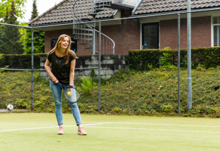 Vrouw speelt tennis in casual kleding op een baan bij Landgoed de Scheleberg, Gelderland, Nederland.