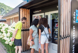 Three people look into a self-service vending machine at Landgoed de Scheleberg, Gelderland, Netherlands.