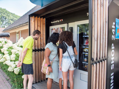 Three people look into a self-service vending machine at Landgoed de Scheleberg, Gelderland, Netherlands.