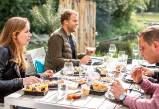 Menschen essen gemeinsam an einem Tisch im Freien bei Landgoed de Scheleberg, Gelderland, Niederlande.