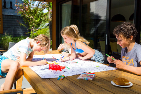 Kinder malen draußen an einem Tisch im Landgoed de Scheleberg, einem Ferienpark in Gelderland, Niederlande.