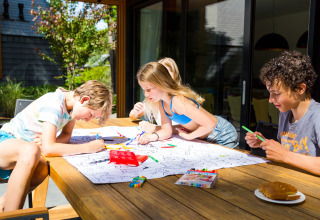 Des enfants dessinent dehors sur une table à Landgoed de Scheleberg, parc de vacances en Gueldre, Pays-Bas.