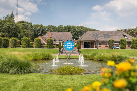 Idyllisches Bild vom Ferienpark Landgoed de Scheleberg in Gelderland, Niederlande mit Springbrunnen und Gebäuden.