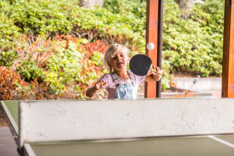 Kind speelt pingpong met batje in Landgoed de Scheleberg, een vakantiepark in Gelderland, Nederland.
