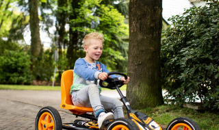 Niño conduciendo un coche a pedales en Landgoed de Scheleberg, parque vacacional en Gelderland, Países Bajos.
