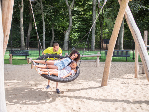 A man pushes two children on a large swing at Landgoed de Scheleberg holiday park, Gelderland, Netherlands.