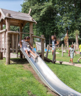 Niños jugando en un tobogán del parque infantil en Landgoed de Scheleberg, Gelderland, Países Bajos.