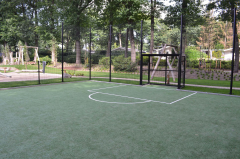 Kunststoff-Fußballplatz mit Zaun, umgeben von Bäumen im Ferienpark Landgoed de Scheleberg, Gelderland, Niederlande.