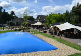 Buitenzone op Landgoed de Scheleberg vakantiepark in Gelderland, Nederland, met blauwe springkussen bij terras.