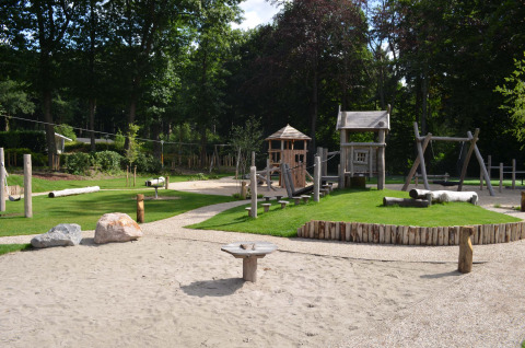 Spielplatz mit Holzgeräten und Sandbereich im Ferienpark Landgoed de Scheleberg, Gelderland, Niederlande.