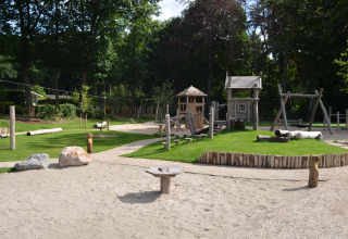 Spielplatz mit Holzgeräten und Sandbereich im Ferienpark Landgoed de Scheleberg, Gelderland, Niederlande.