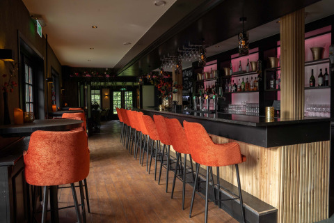 Contemporary bar with orange chairs at Landgoed de Scheleberg holiday park in Gelderland, Netherlands.