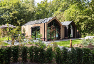Modern wooden holiday cottage surrounded by greenery at Résidence Lage Vuursche park in Utrecht, Netherlands.
