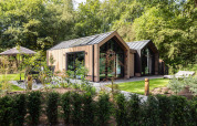 Modern wooden holiday cottage surrounded by greenery at Résidence Lage Vuursche park in Utrecht, Netherlands.