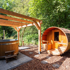 Área de spa al aire libre con sauna de barril y bañera de madera en un parque vacacional de Utrecht.
