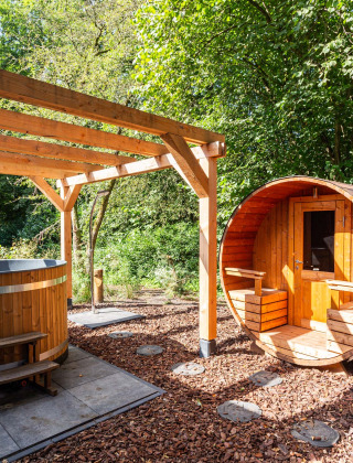 Área de spa al aire libre con sauna de barril y bañera de madera en un parque vacacional de Utrecht.