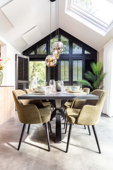 Moderne eetkamer met groene stoelen, zwarte tafel en grote ramen bij Résidence Lage Vuursche, Utrecht, Nederland.