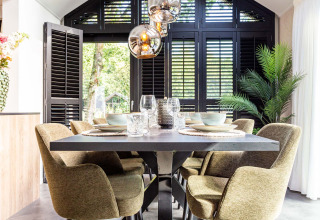 Moderne eetkamer met groene stoelen, zwarte tafel en grote ramen bij Résidence Lage Vuursche, Utrecht, Nederland.