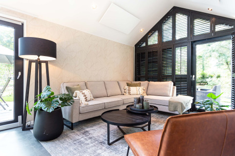 Moderne woonkamer in Résidence Lage Vuursche, Utrecht, met hoekzetel, grote ramen en groene planten.